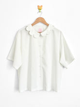 White blouse with a collar on a wooden hanger against a white background